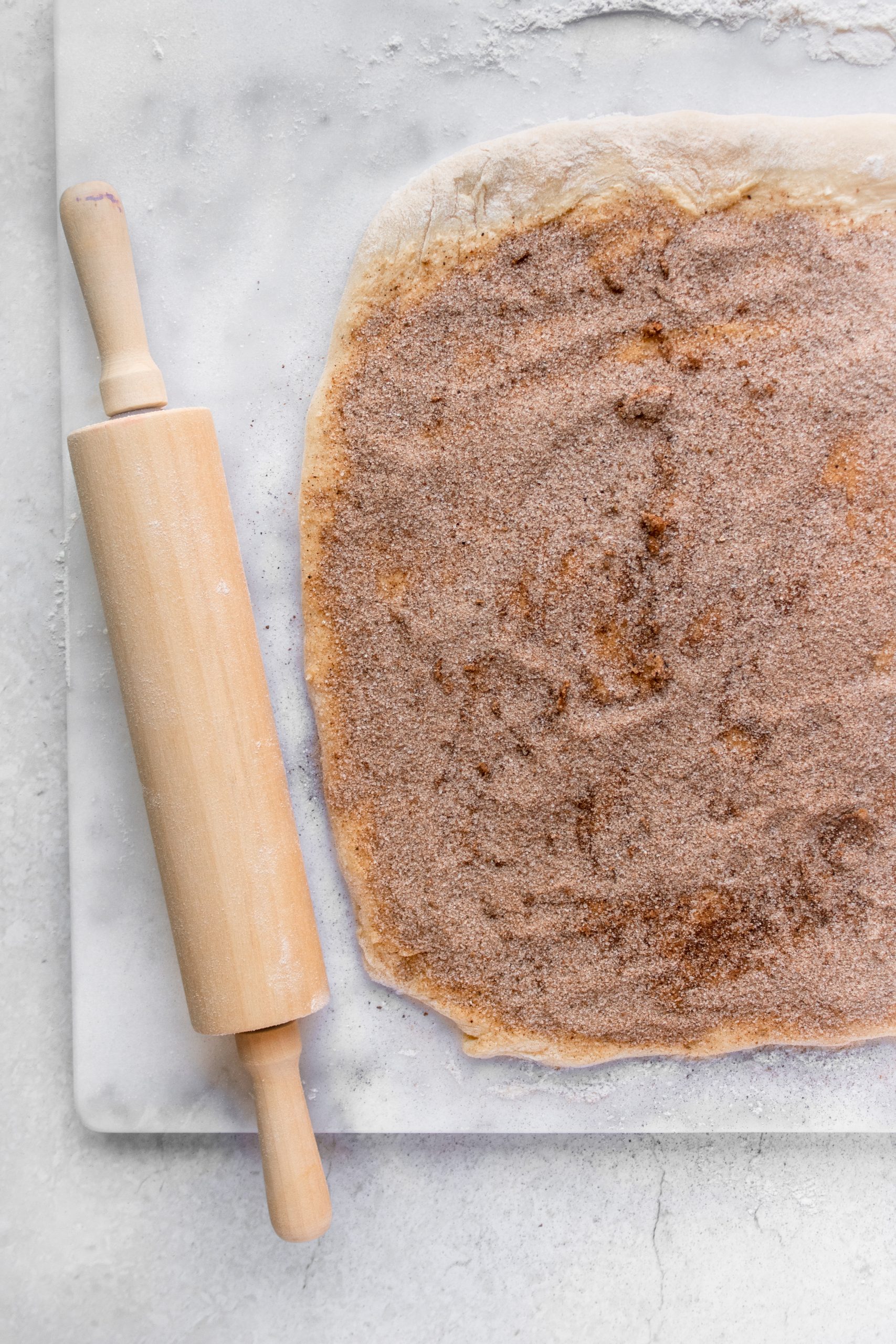 Rolled out cinnamon roll dough covered with butter and chai spiced sugar